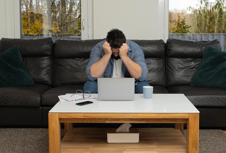 Foto teleurgestelde man die thuis aan een laptop werkt