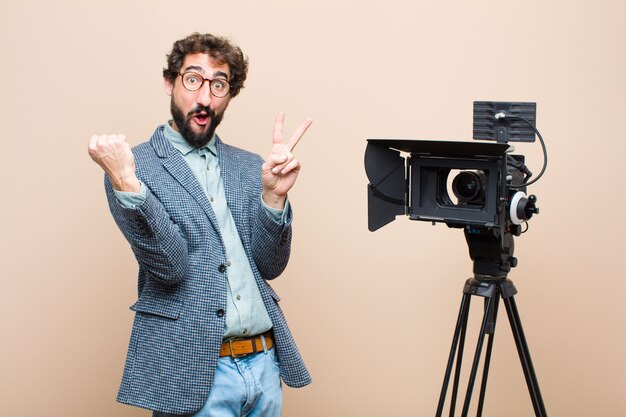 Televisiepresentator glimlachend en op zoek gelukkig, vriendelijk en tevreden, gebaren overwinning of vrede met beide handen