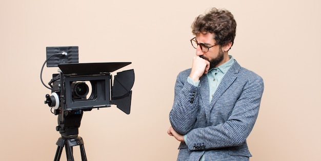 Il presentatore televisivo si sente serio, riflessivo e preoccupato, fissando lateralmente con la mano premuta contro il mento