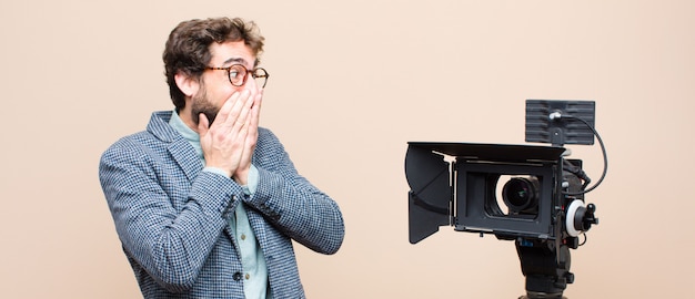 Television presenter looking happy, cheerful, lucky and surprised covering mouth with both hands