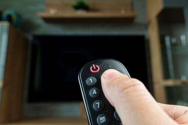 Television remote control changes channels thumb on the tv screen