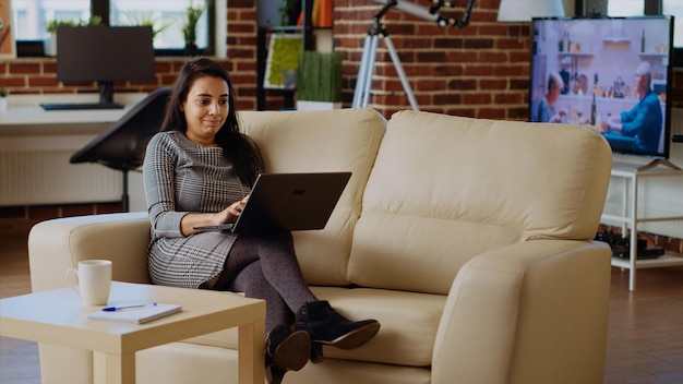 Photo teleworker typing on laptop keyboard lounged on couch at home