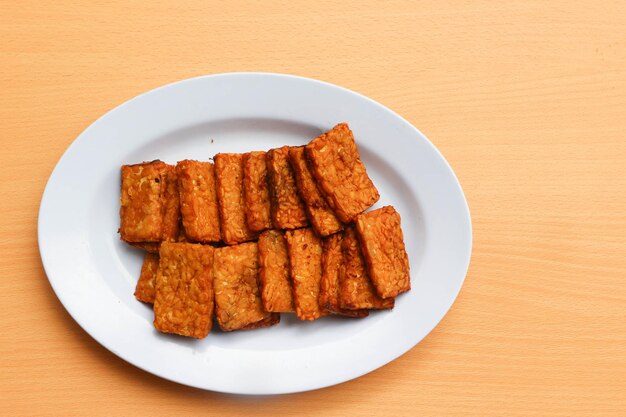 Tempe goreng or fried tempeh is a traditional food from indonesia made from fermented soybean seeds wrapped in banana leaves