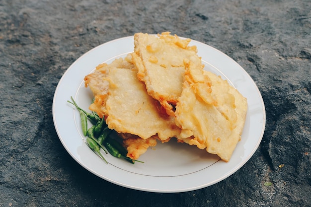 Tempe Mendoan is een soort tempeh gerecht gemaakt van dunne tempeh en gebakken in bloem zodat het lekker en knapperig smaakt met sojasaus in houten plaat geïsoleerd op witte achtergrond