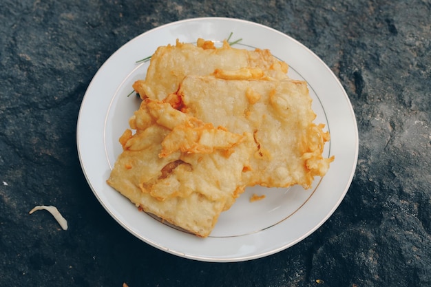 Tempe Mendoan is een soort tempeh gerecht gemaakt van dunne tempeh en gebakken in bloem zodat het lekker en knapperig smaakt met sojasaus in houten plaat geïsoleerd op witte achtergrond