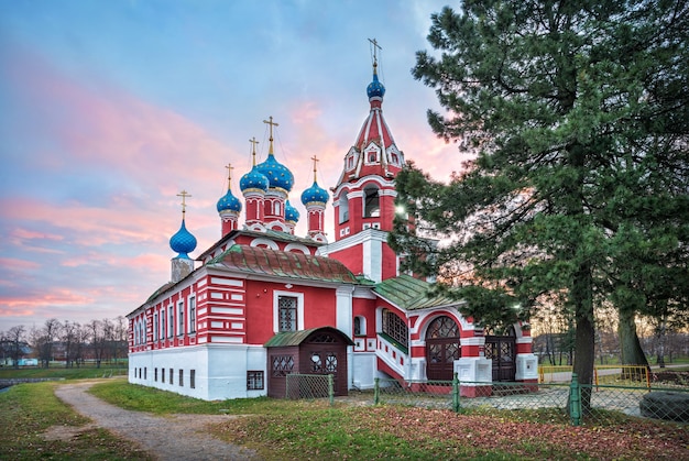 Tempel van Dmitry op het Bloed in het Kremlin van Uglich tegen de achtergrond van een roze ochtendhemel op een herfstochtend. Bijschrift: Kremlinstraat