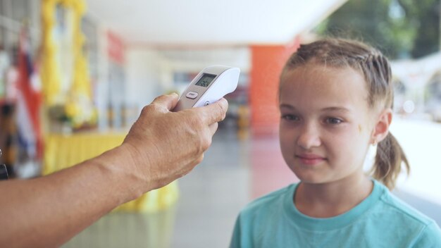 Temperature check at a supermarket of little girl grocery store
with thermal imaging camera installed coronavirus covid19