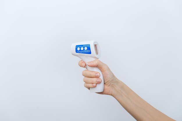 Temperature measurement gun in doctor hands close-up of doctor wearing protective surgical mask