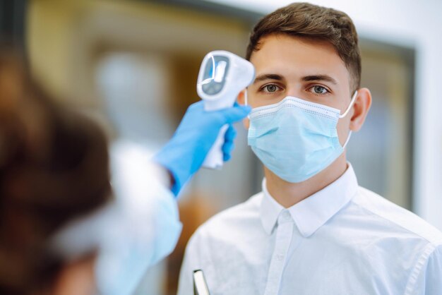 Temperatuurscreening kantoormedewerkers Ziektebestrijding expert in vizier met een infrarood thermometer