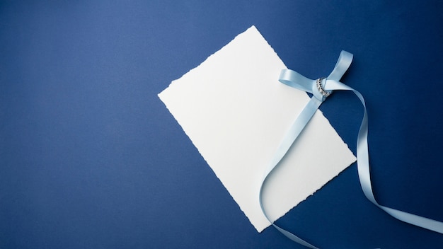 Modello per inviti, saluti. su uno sfondo blu, un foglio di carta bianco, una busta, un quaderno, un anello con pietre e candele decorative. design minimalista per matrimonio, compleanno.