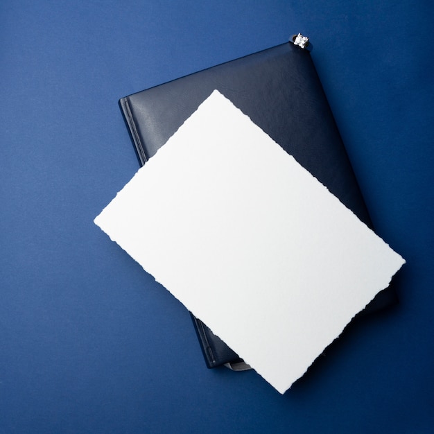 Modello per inviti, saluti. su uno sfondo blu, un foglio di carta bianco, una busta, un quaderno, un anello con pietre e candele decorative. design minimalista per matrimonio, compleanno.