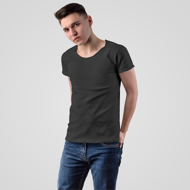 Template male black t-shirt on a young guy in blue jeans with hands in his pocket on a white background, front view. Mockup of fashionable empty clothes for presentation of design and pattern.