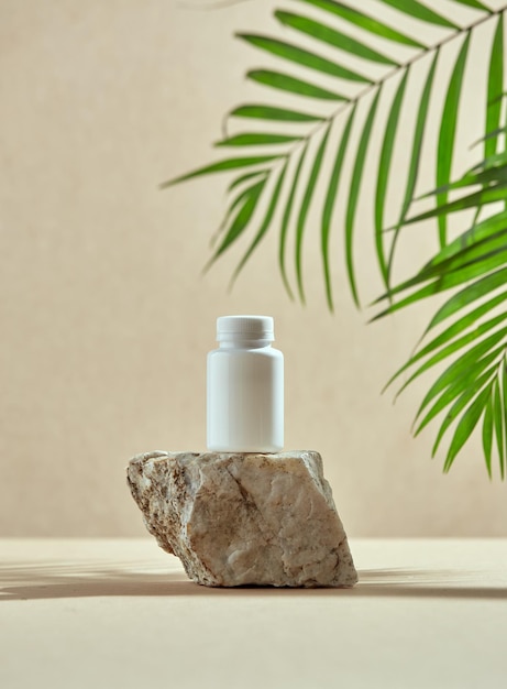Template white plastic jar on stone pedestal with palm leaves dietary supplements vitamins