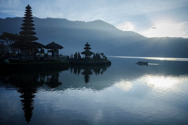 Foto tempio accanto al lago e silhouette di montagne contro un cielo nuvoloso