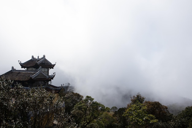 山を背景にした雲の中の寺院