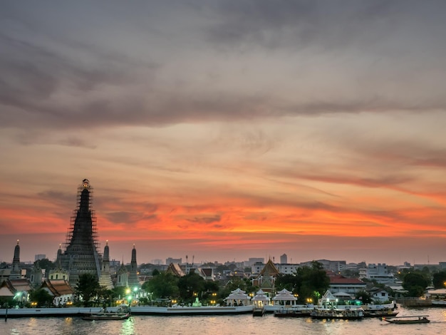 タイのバンコクの夕暮れの夕方の空の下、チャオプラヤー川の夜明けの寺院のメインパゴダ側