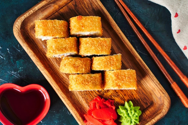 Tempura fried rolls with salmon shrimp tuna caviar and cheese on dark background close up