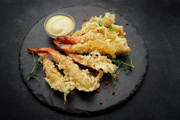 Tempura garnalen met saus op een donkere ondergrond