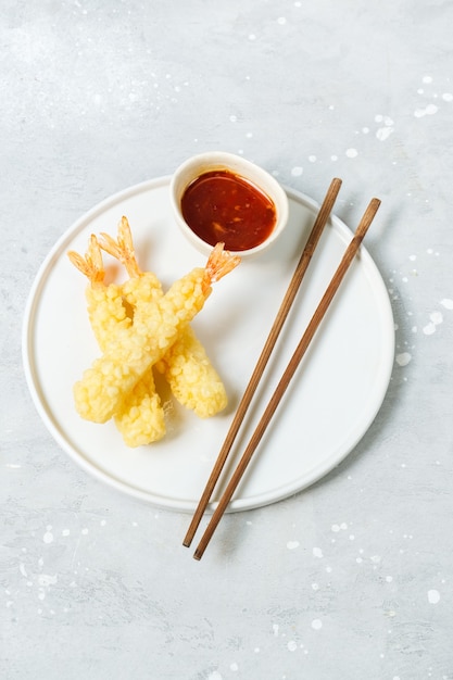 Tempura garnalen met zoete chilisaus op een witte plaat. Bezorging van Aziatische gerechten