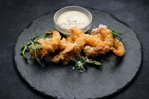 Tempura shrimp on a dark plate on dark concrete