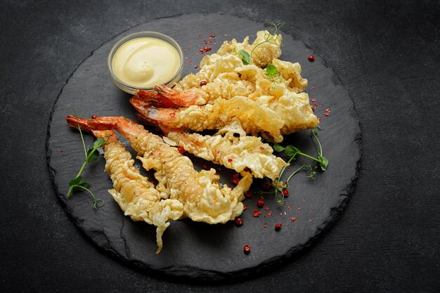 Tempura shrimps with sauce on a dark background