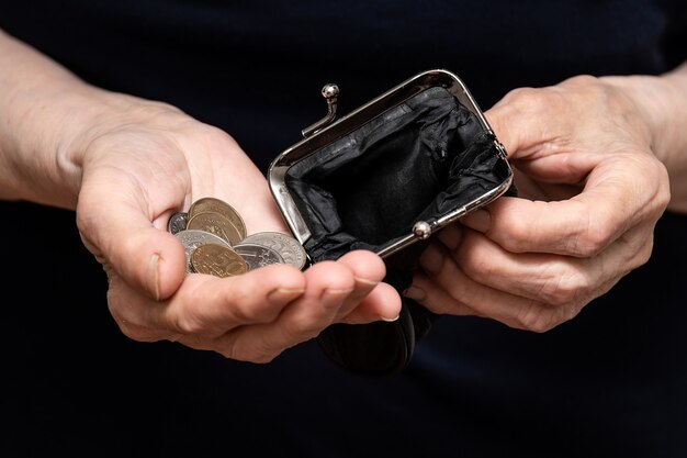 Ten-ruble coins are poured into the hands of a pensioner, the concept of poverty