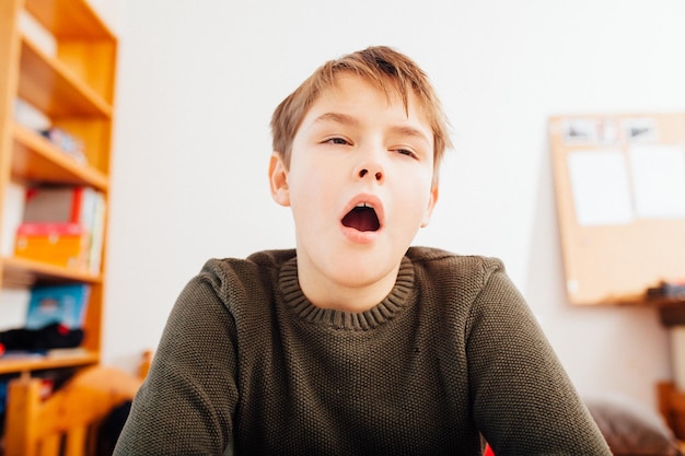 Photo ten year old school boy yawning in home video schooling situation