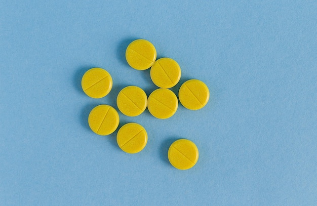 ten yellow pills on a blue background