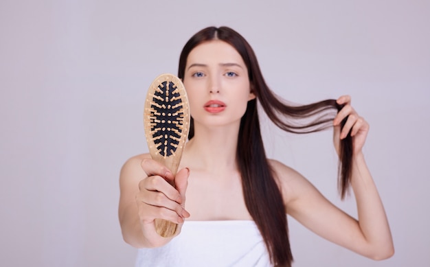 A tender brunette with a wooden comb holds on to her hair.