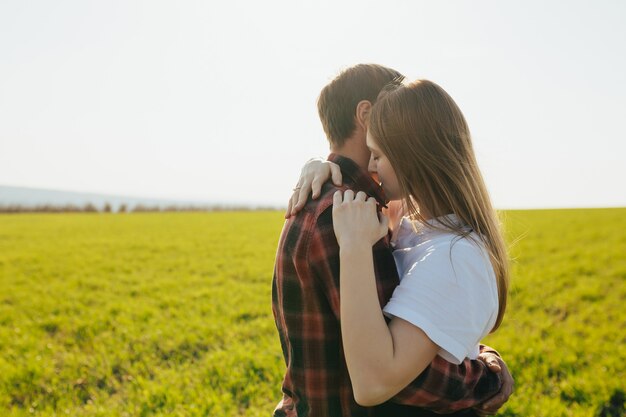 緑の野原で抱き合って抱き合う優しいカップル。春のラブストーリー。