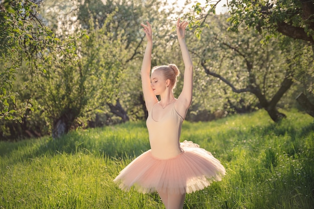 Tender dancer woman in green flowers landscape at sunset