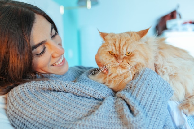 ベッドで彼女の猫をなでる優しい女性