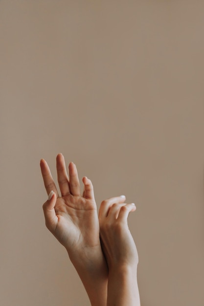 Tender handen van het meisje worden opgeheven op een gewone achtergrond Verticale foto