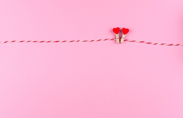 Tender little heart symbol of St. Valentine's day on a clothespin and string creative postcard, copy space, flat lay on pink background