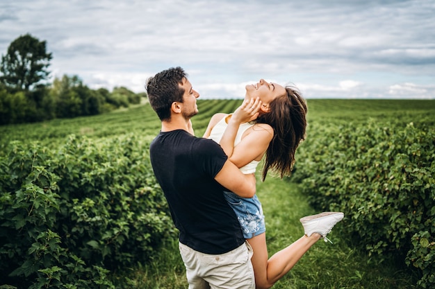 A tender loving couple walking in a field of currant. Man whirls woman in her arms. Love story