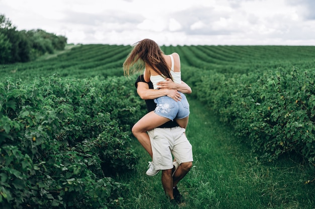 A tender loving couple walking in a field of currant. Man whirls woman in her arms. Love story