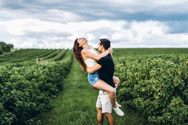 A tender loving couple walking in a field of currant. Man whirls woman in her arms. Love story