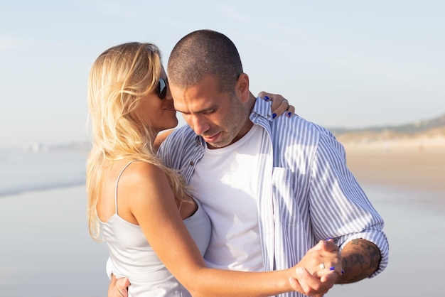 Tender male and female couple spending time at beach. Husband and wife in casual clothes hugging and dancing on summer day. Vacation, happiness, relationship concept