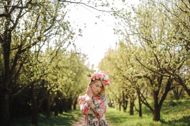 Tender portrait of beautiful blonde woman dressed in flower dress and pink wreath