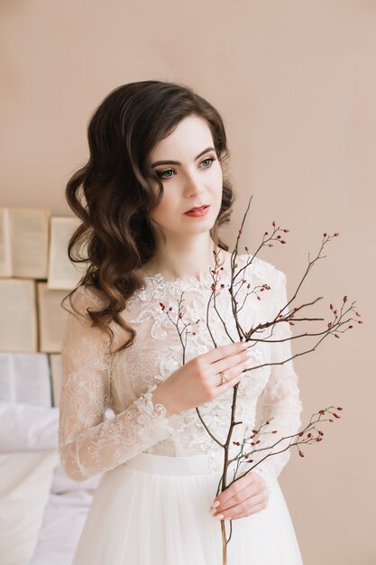 Tender pure portrait of a young beautiful woman with flowers on beige 