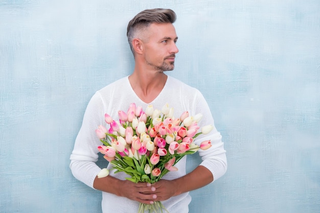 Tender tulips for her. For someone special. Man with tulips bouquet. Handsome man holding pink tulips. Attractive man with flowers. Sexy man carry gift for valentines day or birthday celebration.