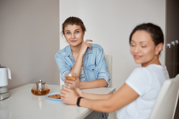 Donna tenera che sorride mentre abbraccia la tazza preferita con il tè