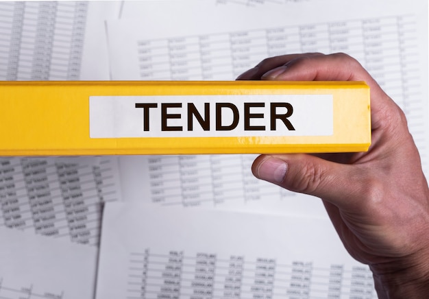 Tender word on office folder in male hand business procurement concept