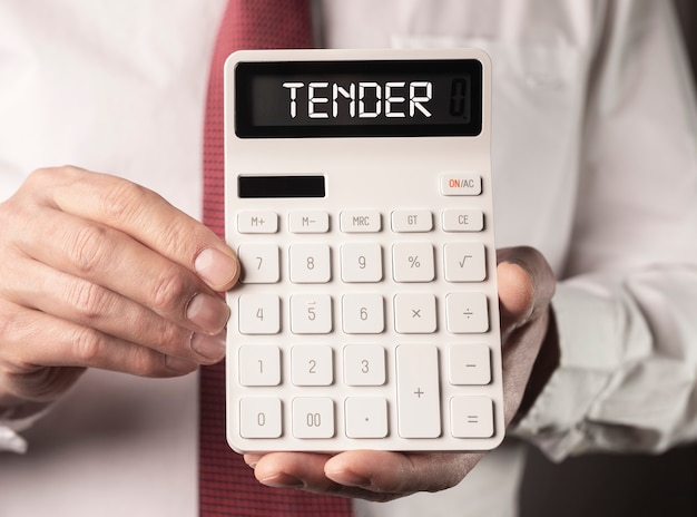 Tender word on white calculator in male hands business public offer