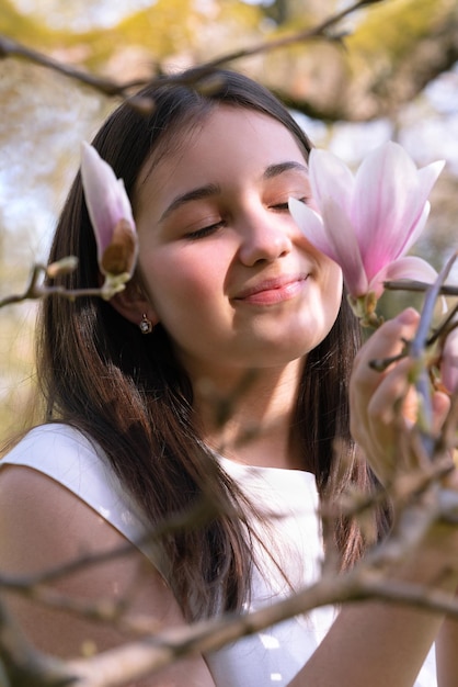 목련 꽃에 닫힌된 눈을 가진 부드러운 어린 소녀 얼굴 근접 촬영