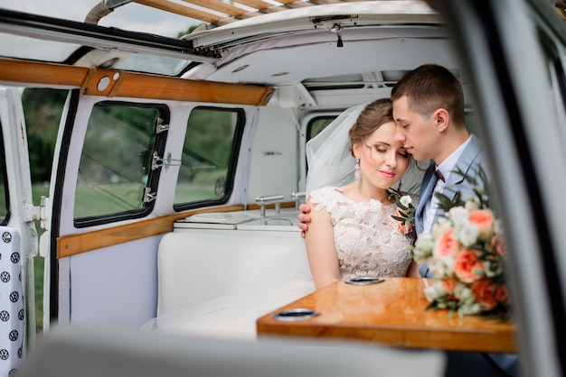 Tender young wedding couple poses in an old bus