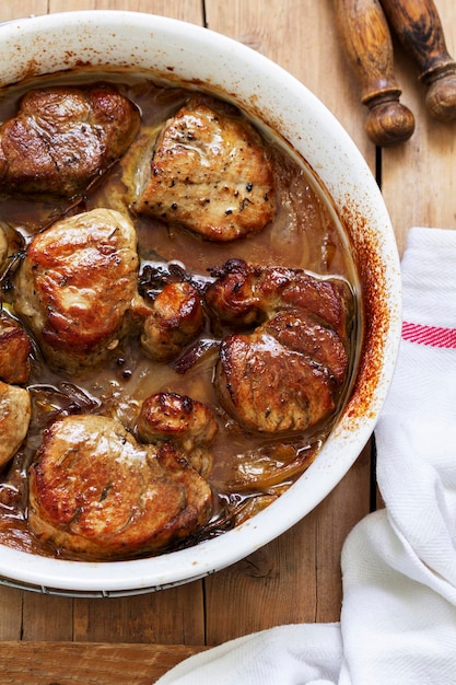 Foto filetto al forno in salsa di cipolla con erbe aromatiche su una tavola di legno in stile rustico