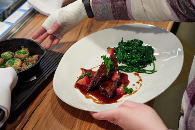 Tenderloin steak wrapped in bacon with red sauce and spinach.