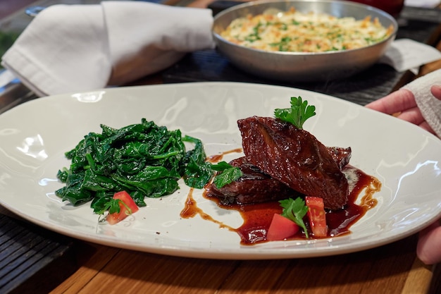 Tenderloin steak wrapped in bacon with red sauce and spinach.