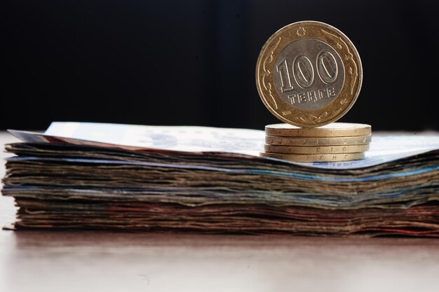Tenge. Kazakhstan money. A stack of coins lies on a pack of bills close-up.